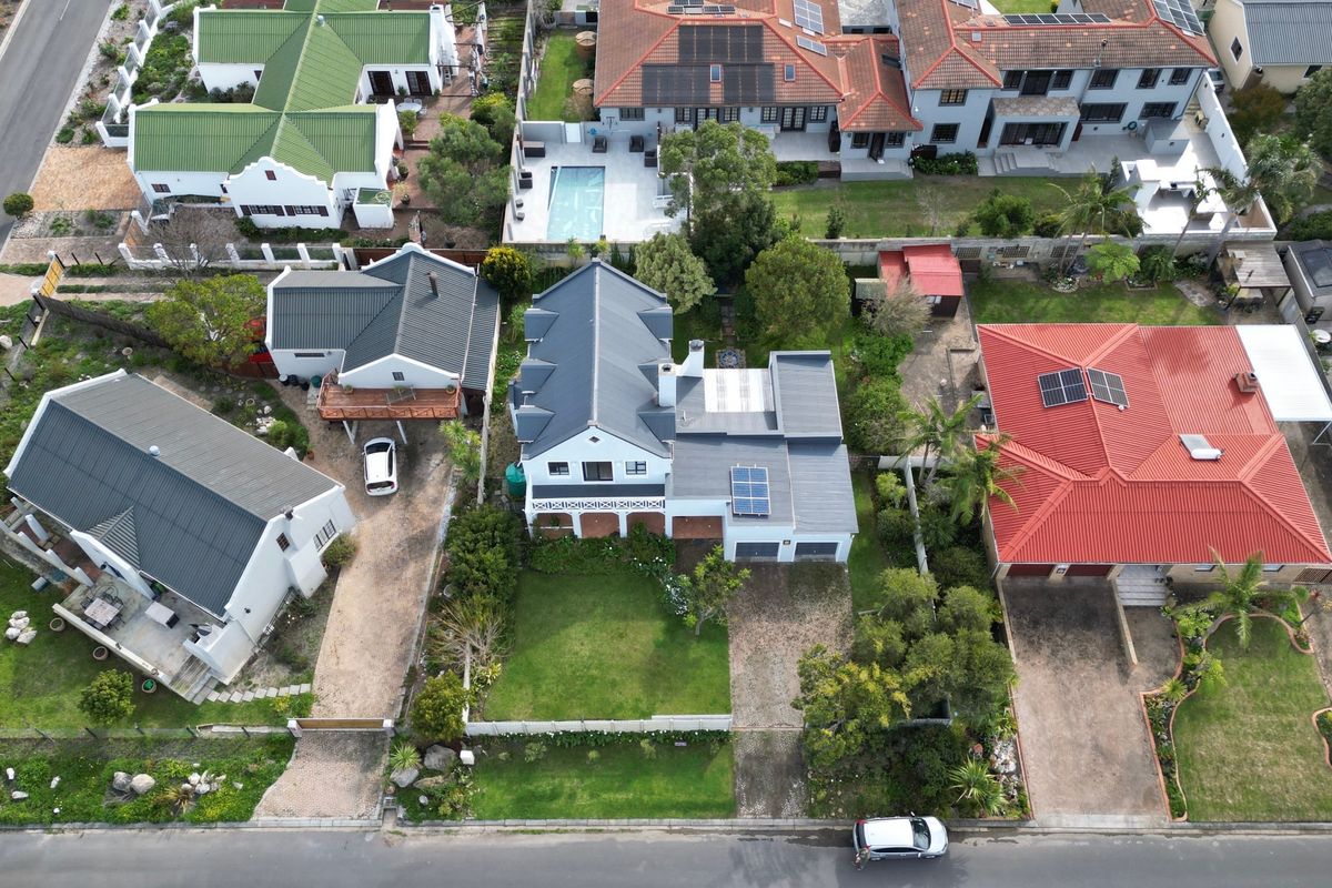 Aerial view of the property showcasing the roof structure, solar panels, front garden, and paved driveway within the residential neighborhood.