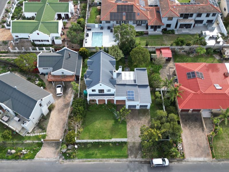 Aerial view of the property showcasing the roof structure, solar panels, front garden, and paved driveway within the residential neighborhood.