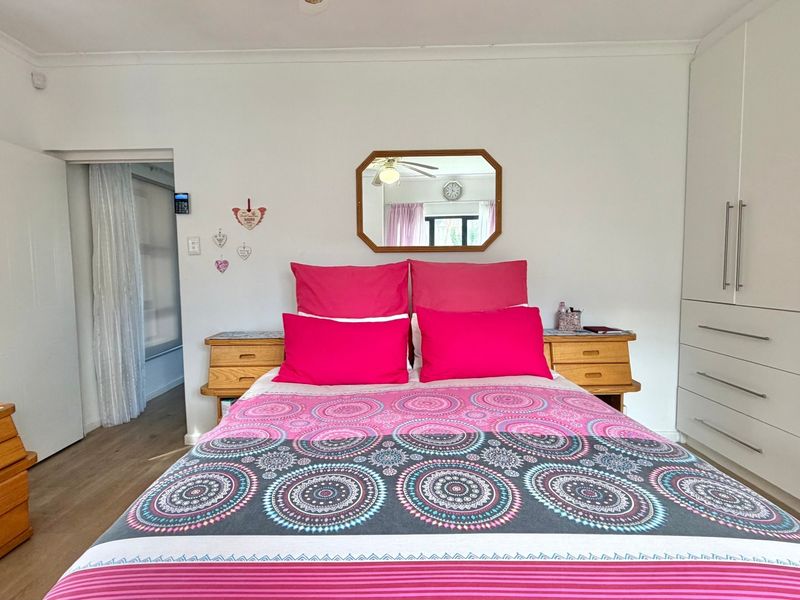A well-maintained bedroom featuring built-in wardrobes, a ceiling fan, and light-toned laminate flooring, offering a clean and functional living space.