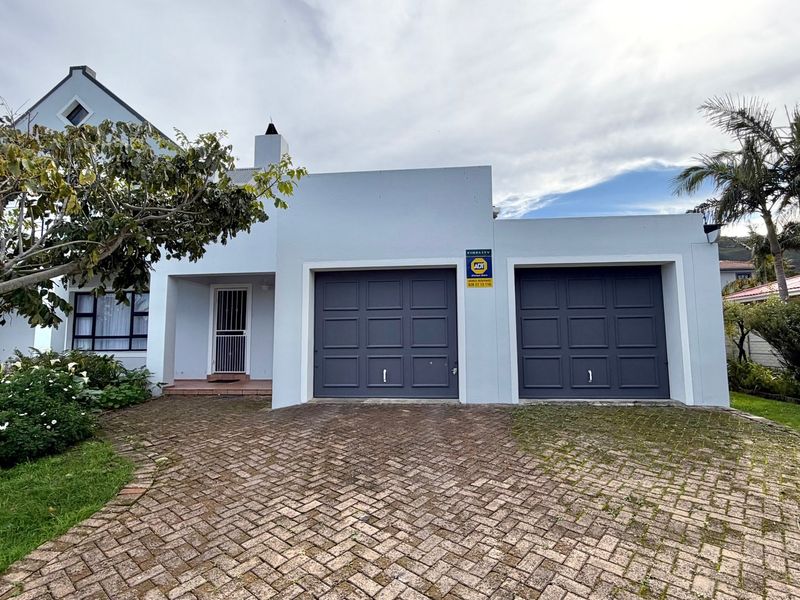 Front elevation of the house featuring a double garage, paved driveway, and a secure entrance with a security gate.