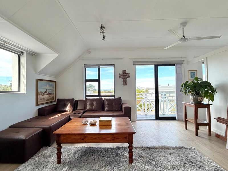 Bright living room featuring laminate flooring, a ceiling fan, and sliding glass doors leading to an outdoor balcony area.