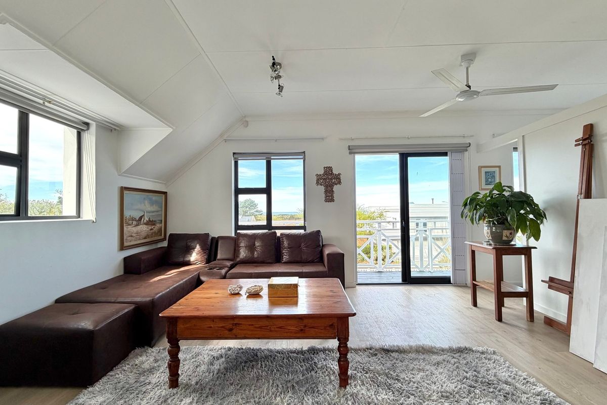 Bright living room featuring laminate flooring, a ceiling fan, and sliding glass doors leading to an outdoor balcony area.