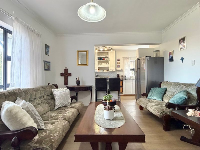 Open-plan living area featuring laminate flooring and a view through to the kitchen, creating a functional and connected living space.