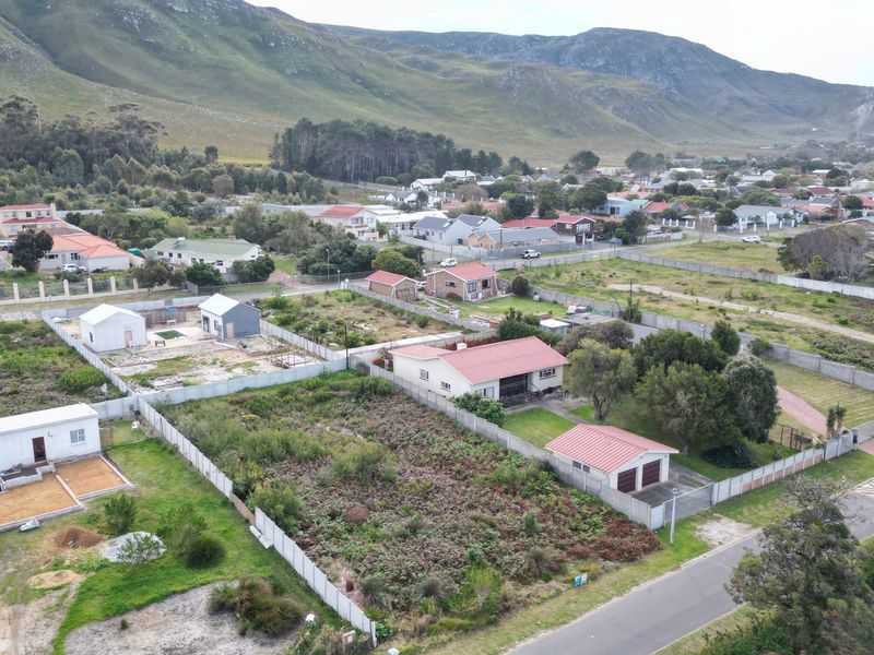 Aerial view of a residential neighborhood featuring vacant land plots, established homes, and surrounding mountain landscape.
