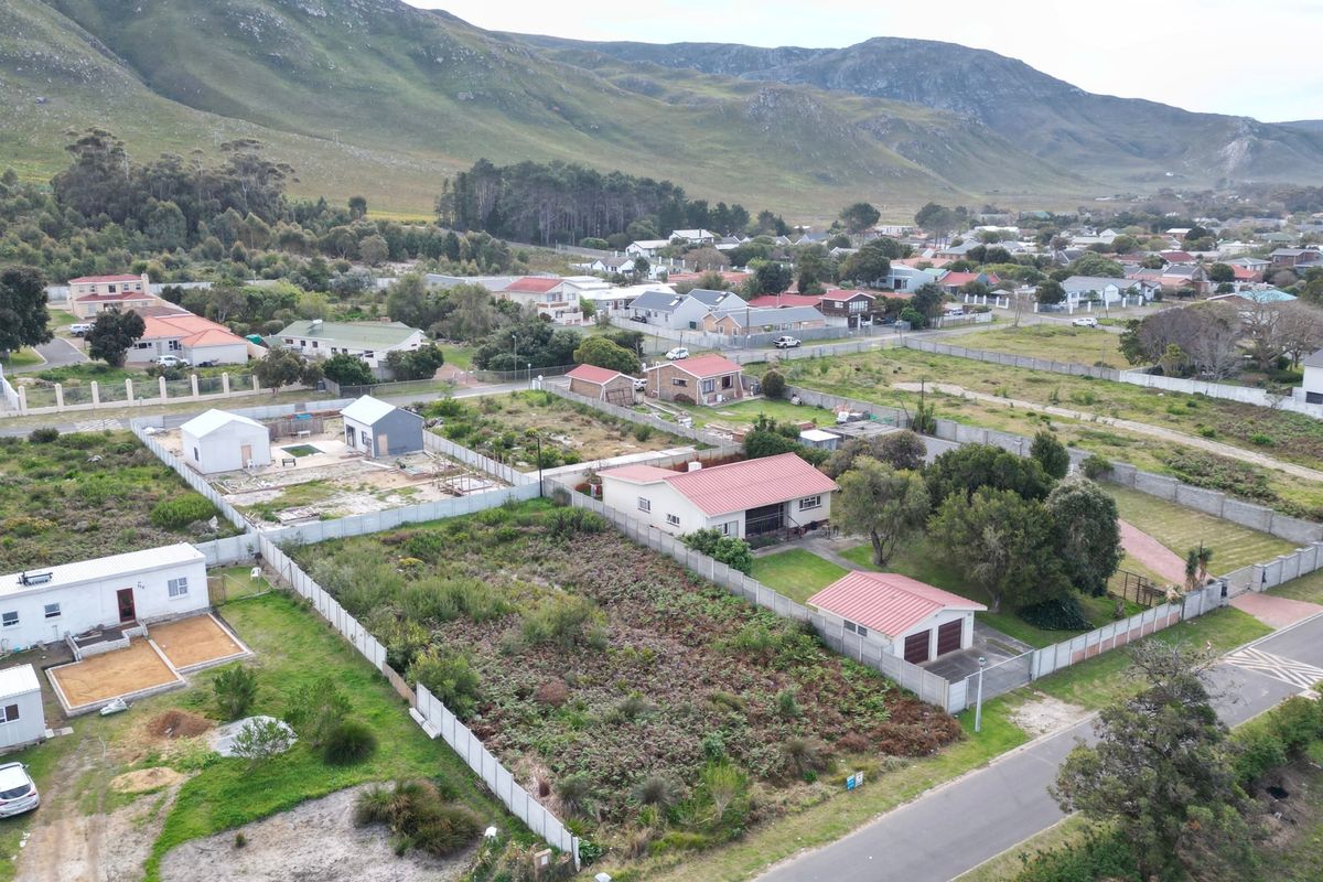 Aerial view of a residential neighborhood featuring vacant land plots, established homes, and surrounding mountain landscape.