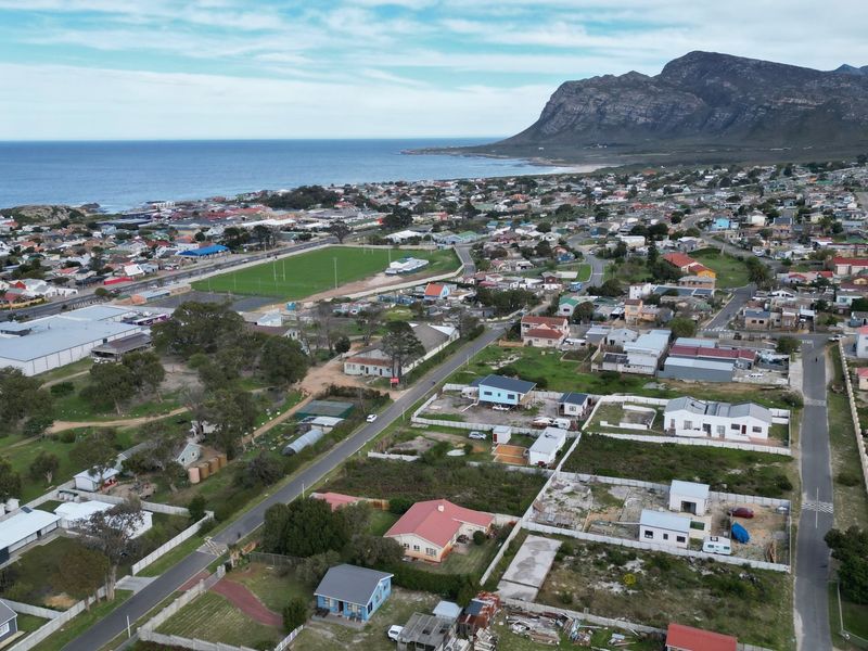 An aerial view of a coastal residential neighborhood featuring mountain views and proximity to the ocean.