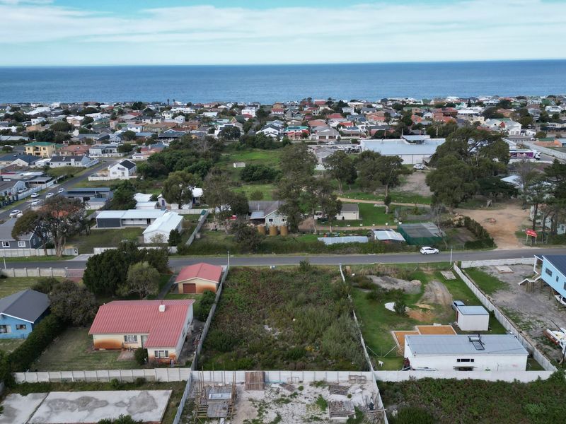 An aerial view of a residential vacant land plot situated in a coastal neighborhood, showing surrounding properties and proximity to the ocean.