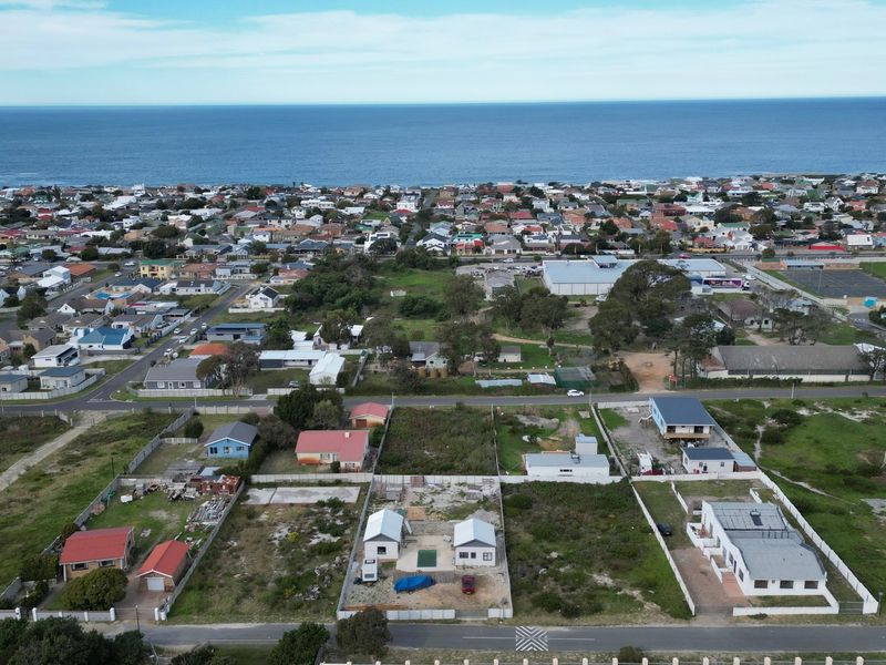 Aerial view of a coastal residential neighborhood featuring vacant land plots and established housing near the ocean.