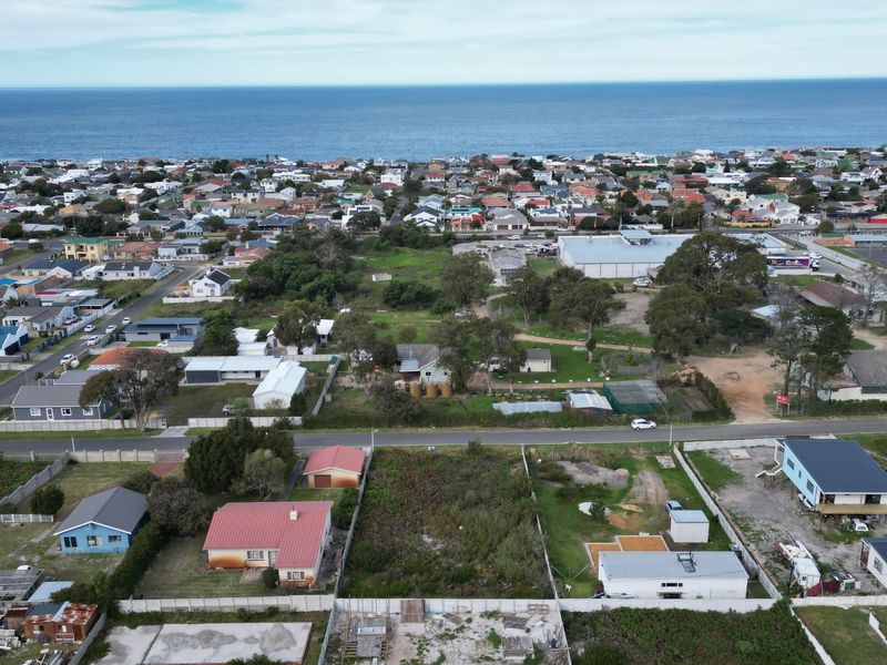 Aerial view of a residential neighborhood featuring a vacant plot of land with proximity to the coastline.