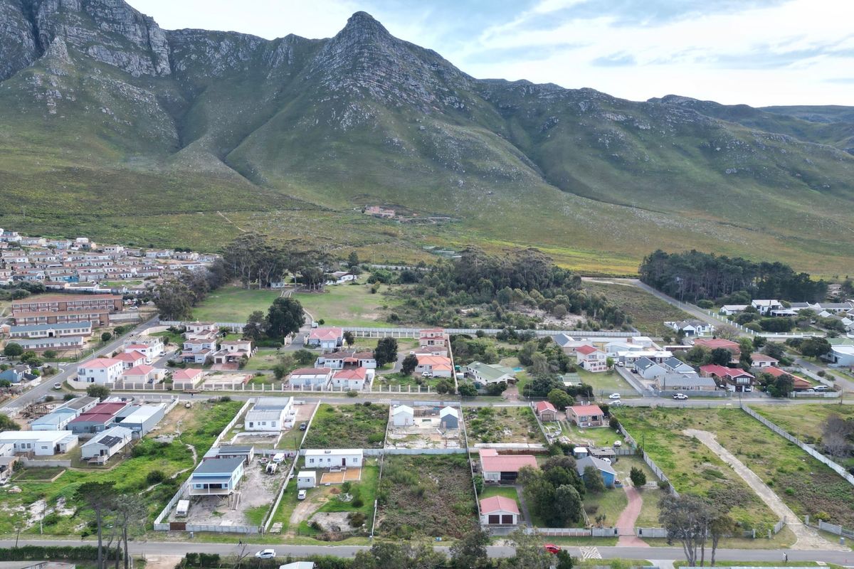 Aerial view of a residential neighborhood featuring vacant land plots set against a scenic mountain backdrop.