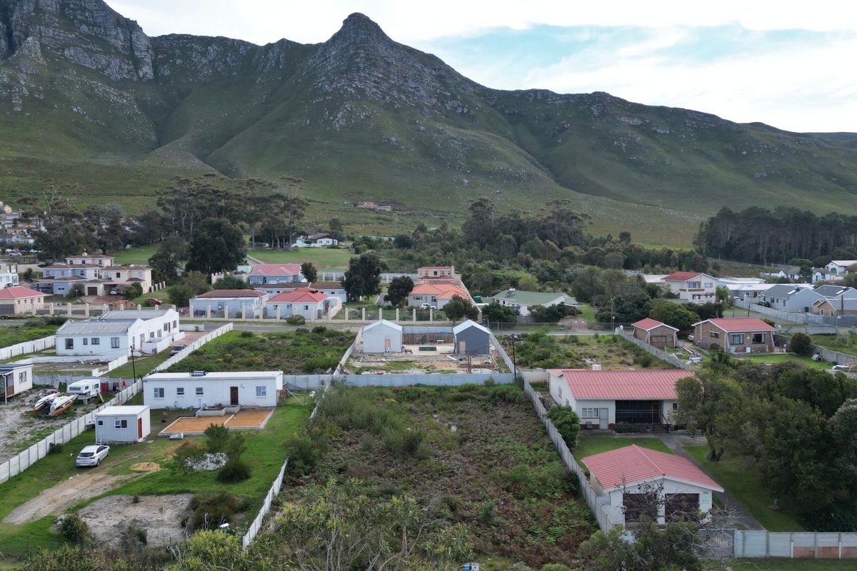 Aerial view of a residential neighborhood featuring vacant land plots and established homes set against a scenic mountain backdrop.