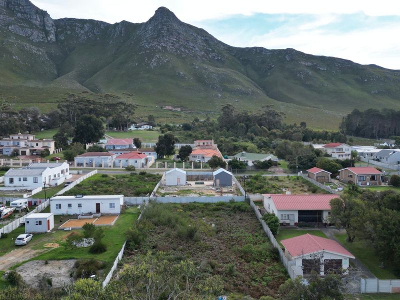 Aerial view of a residential neighborhood featuring vacant land plots and established homes set against a scenic mountain backdrop.