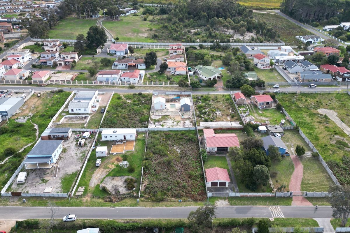An aerial view of a residential neighborhood featuring multiple vacant and developed plots with established perimeter fencing and access roads.