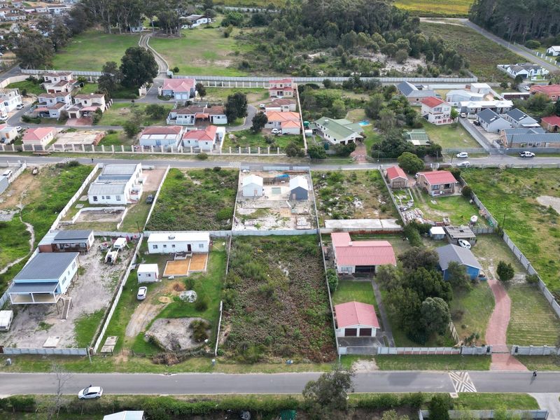 An aerial view of a residential neighborhood featuring multiple vacant and developed plots with established perimeter fencing and access roads.