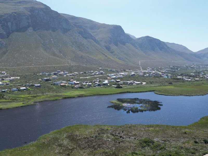 An aerial view of a residential coastal area featuring a natural lake and scenic mountain backdrop.