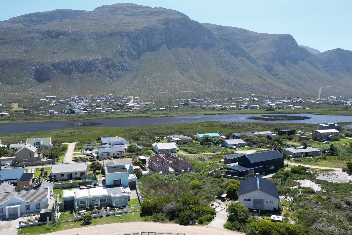 An aerial view of a residential neighborhood set against a scenic mountain range and adjacent to a natural wetland area.