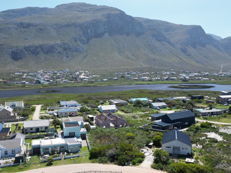 An aerial view of a residential neighborhood set against a scenic mountain range and adjacent to a natural wetland area.