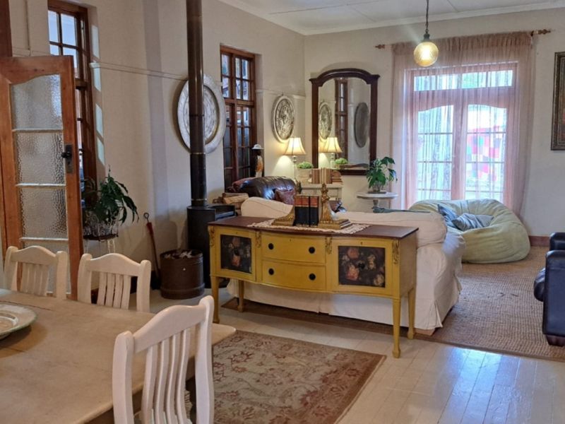 Spacious open-plan living and dining area featuring timber flooring, a freestanding fireplace, and access to the outdoors through classic french doors.