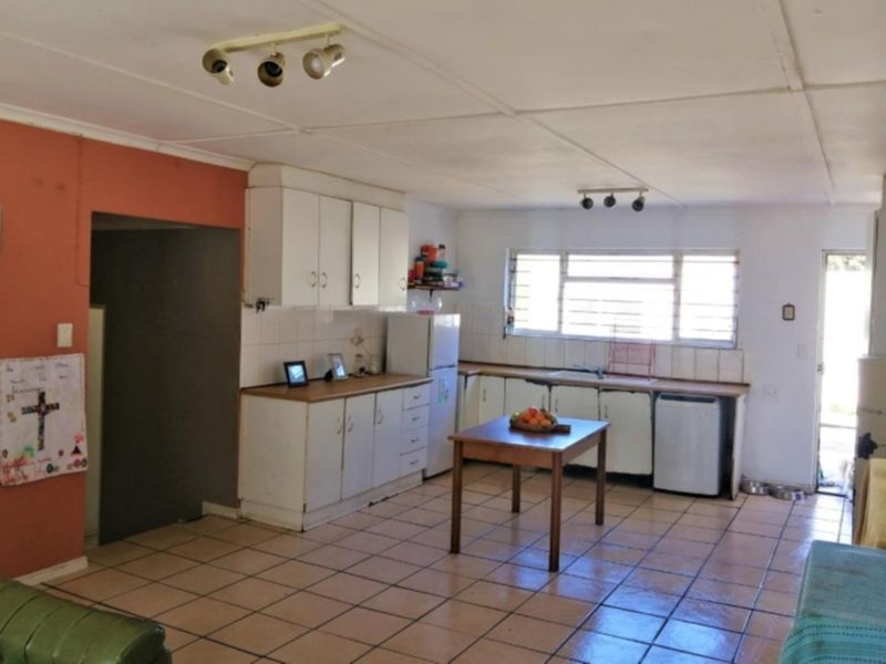 A functional kitchen featuring built-in cabinetry, laminate countertops, and tiled flooring, offering a practical layout with potential for modern updates.