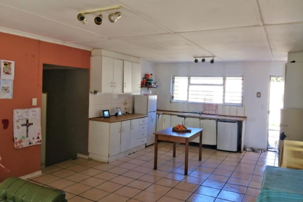 A functional kitchen featuring built-in cabinetry, laminate countertops, and tiled flooring, offering a practical layout with potential for modern updates.