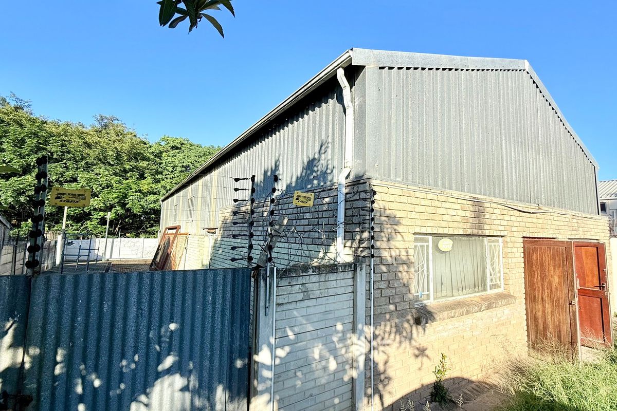 Rear view of an industrial property featuring corrugated metal cladding, face brick walls, and perimeter electric fencing.