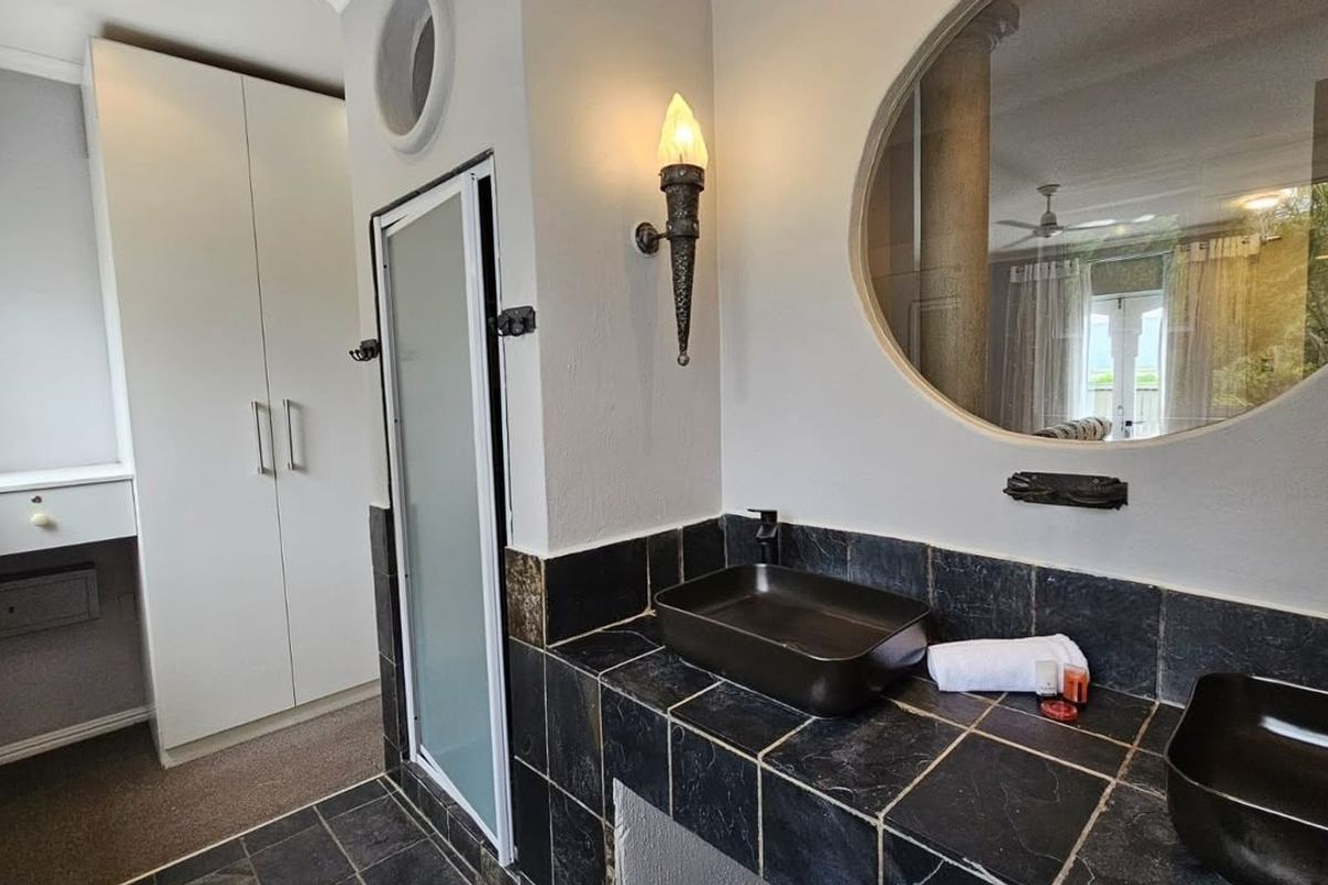 A bathroom featuring a tiled vanity with dual vessel sinks, built-in cabinetry, and decorative wall lighting.