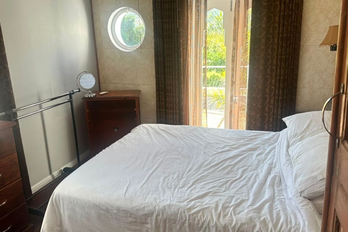 A bedroom featuring textured wallpaper, a unique porthole window, and a glass door providing access to an outdoor area.