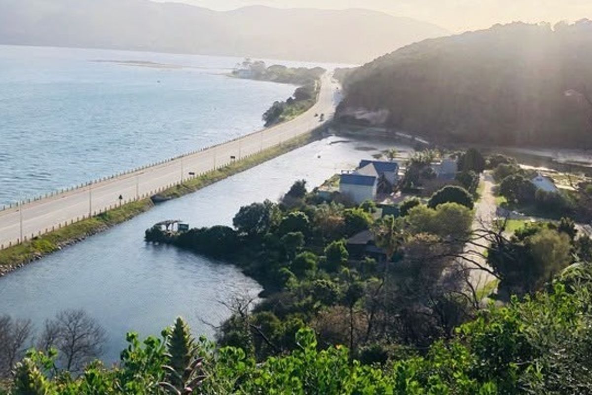 A scenic elevated view overlooking the coastal road, lagoon, and surrounding landscape, highlighting the property's prime location.