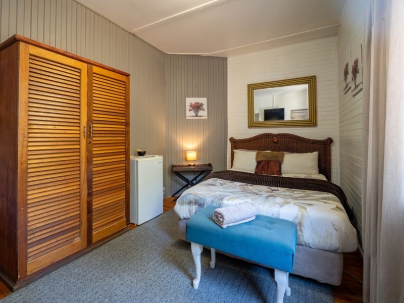 A cozy bedroom featuring timber wall paneling, a built-in wardrobe, and warm timber flooring, offering a comfortable and rustic lodge-style atmosphere.