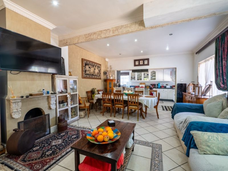 Spacious open-plan living and dining area featuring a fireplace, tiled flooring, and an integrated kitchen with cabinetry.