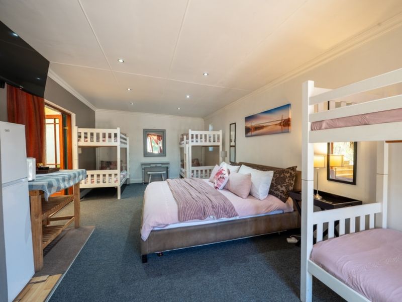 Spacious bedroom featuring multiple bunk beds and a central double bed, finished with recessed downlighting and carpeted flooring.