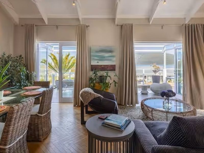 Spacious open-plan living and dining area featuring elegant herringbone timber flooring, vaulted ceilings with exposed rafters, and direct access to a balcony with views.