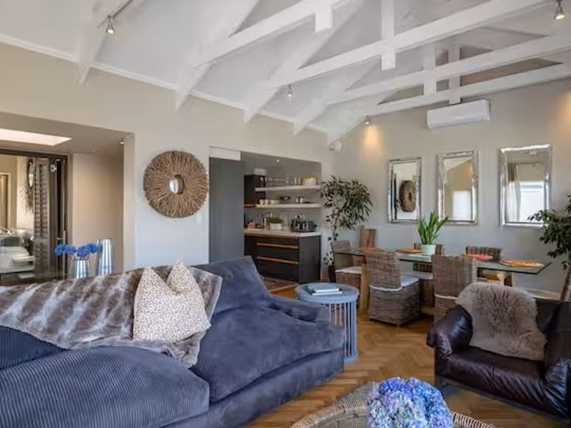 Spacious open-plan living and dining area featuring vaulted ceilings with exposed rafters, herringbone parquet flooring, and a modern split-system air conditioning unit.