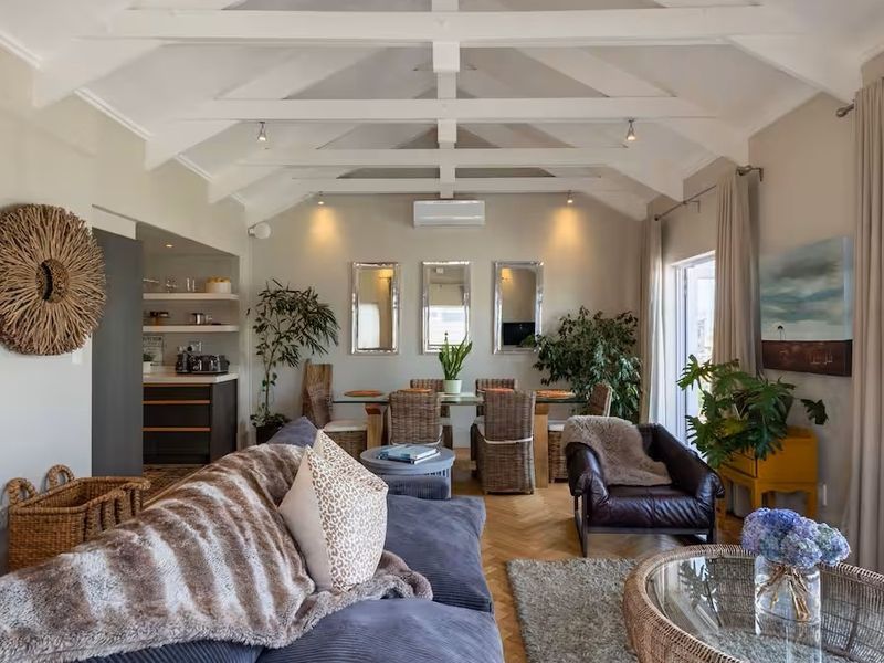 Spacious open-plan living and dining area featuring a vaulted ceiling with exposed beams, herringbone parquet flooring, and direct access to an outdoor patio.
