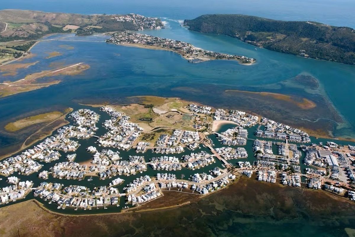 An expansive aerial view of the residential estate situated on a peninsula, showcasing the surrounding lagoon, waterways, and coastal landscape.
