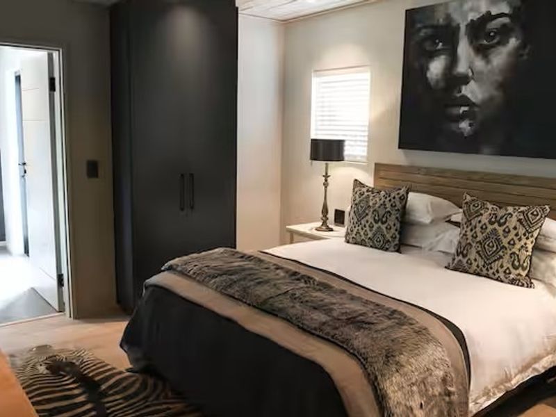 A well-appointed bedroom featuring a built-in wardrobe, timber headboard, and an adjoining en-suite bathroom with modern fixtures.