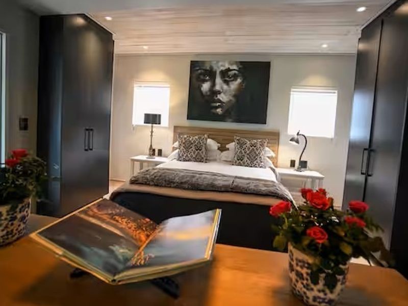 A well-appointed bedroom featuring dark built-in cupboards, recessed ceiling lighting, and decorative timber-look ceiling paneling.