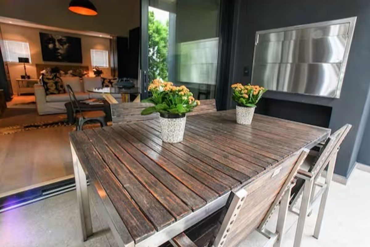 A covered balcony featuring a built-in stainless steel braai and seamless access to the interior living area through large sliding glass doors.