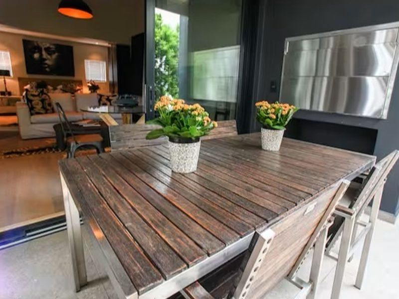 A covered balcony featuring a built-in stainless steel braai and seamless access to the interior living area through large sliding glass doors.