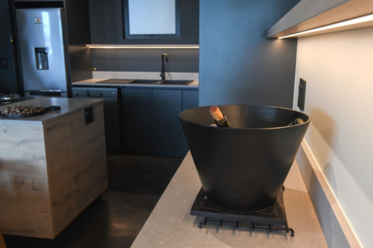 Modern kitchen featuring dark cabinetry, stone countertops, a functional island, and integrated under-cabinet lighting for a sleek, contemporary aesthetic.