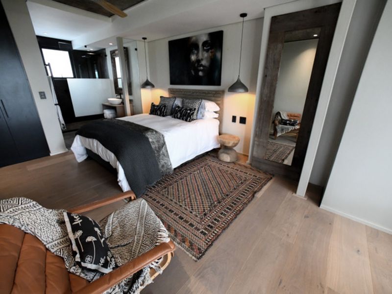 A modern, well-appointed bedroom featuring hardwood flooring, stylish pendant lighting, and an integrated en-suite bathroom area.