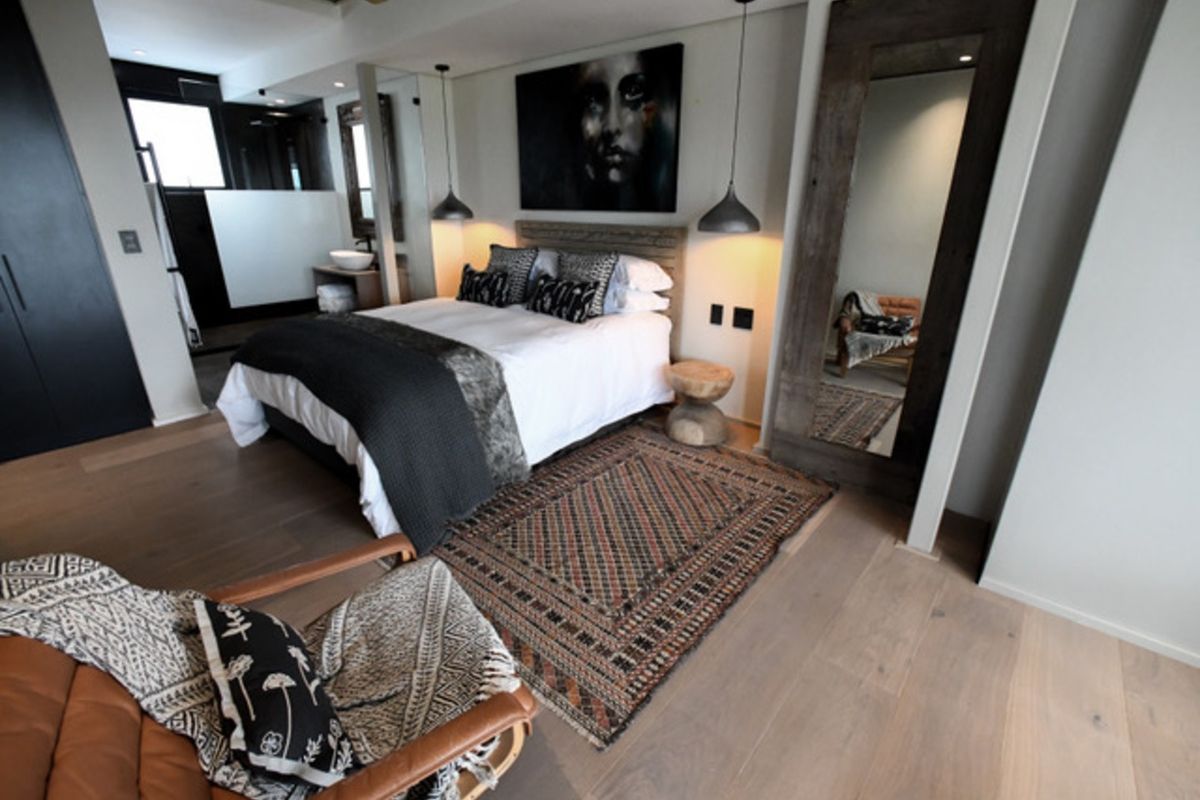 A modern, well-appointed bedroom featuring hardwood flooring, stylish pendant lighting, and an integrated en-suite bathroom area.