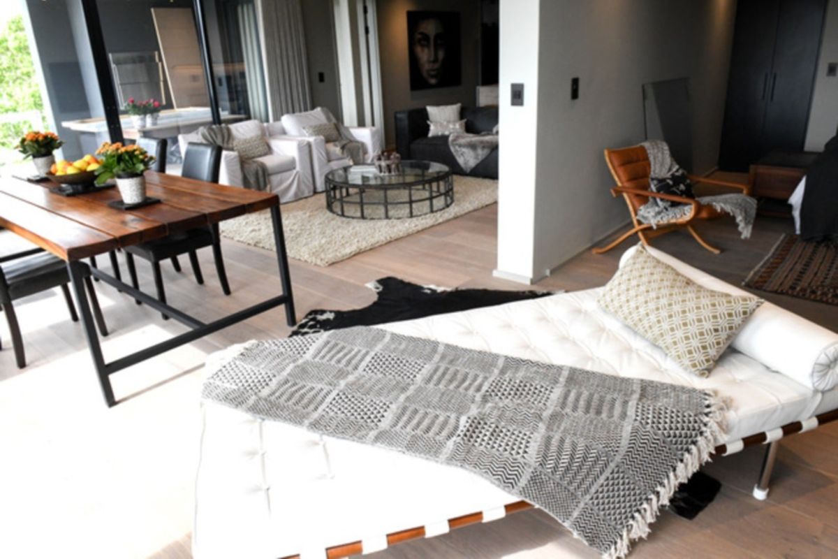 Spacious open-plan living and dining area featuring light hardwood flooring and large sliding glass doors leading to an outdoor patio space.