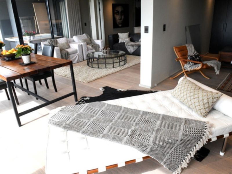 Spacious open-plan living and dining area featuring light hardwood flooring and large sliding glass doors leading to an outdoor patio space.
