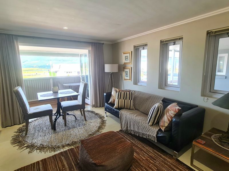 An open-plan living and dining area featuring neutral walls, tiled flooring, and large sliding doors that open onto a balcony with scenic views.