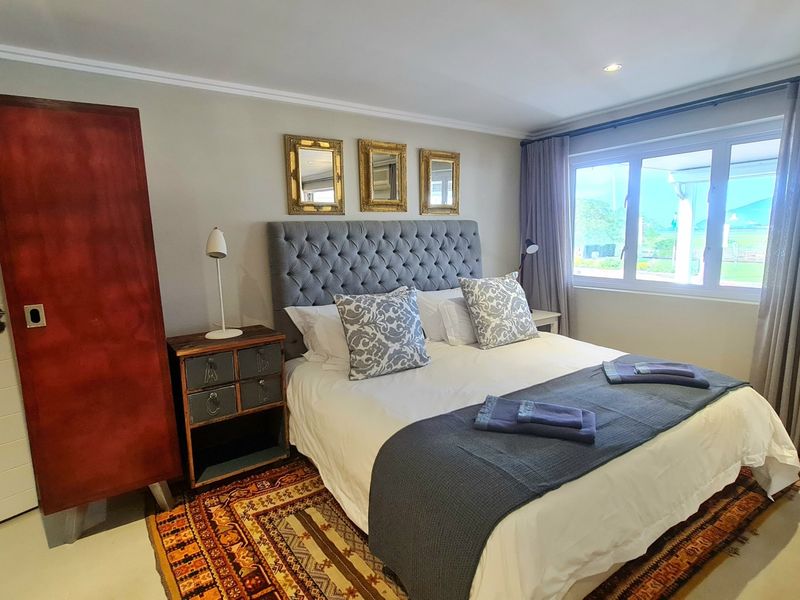 A well-maintained bedroom featuring neutral walls, recessed lighting, an integrated air conditioning unit, and large windows with floor-to-ceiling curtains.