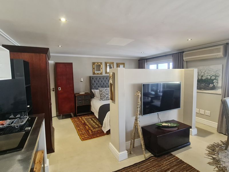 An open-plan studio apartment featuring a kitchenette, sleeping area, and living space separated by a central partition wall with integrated air conditioning.