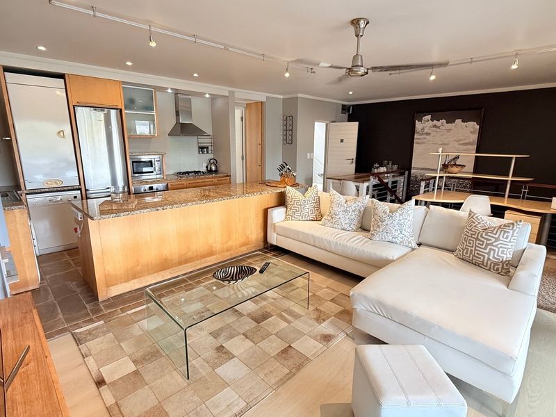 Spacious open-plan living area featuring a modern kitchen with granite countertops, integrated appliances, and a comfortable lounge space with neutral finishes.