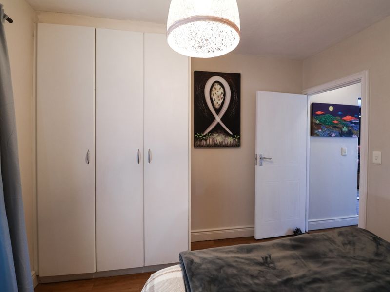 A well-maintained bedroom featuring built-in wardrobes, laminate flooring, and neutral wall finishes, providing a clean and functional living space.