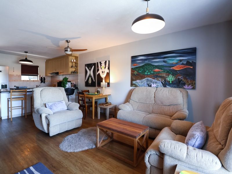 Open-plan living area featuring a functional kitchen with island, laminate flooring, and integrated lighting, creating a cohesive and versatile living space.